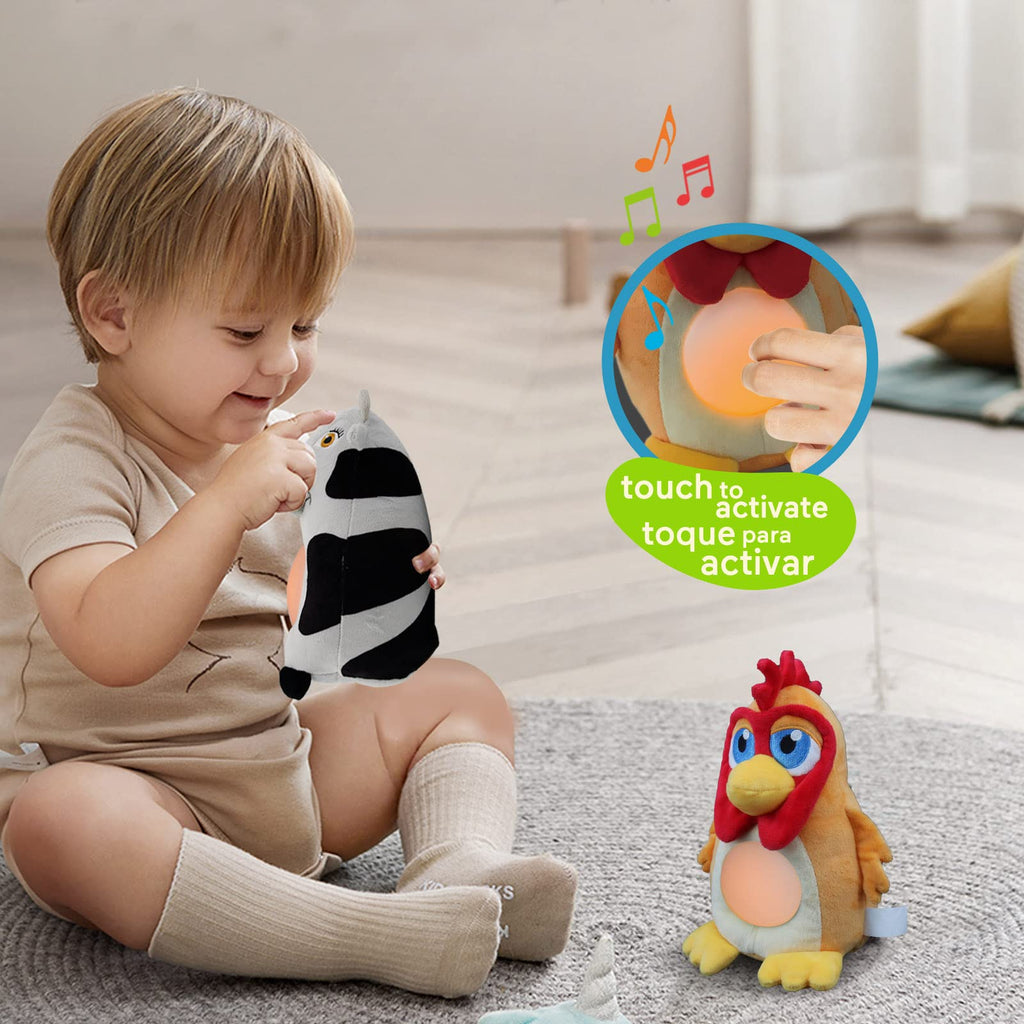 A young child playing with a musical cow toy with a touch-activated light feature, sitting next to a plush chicken toy.