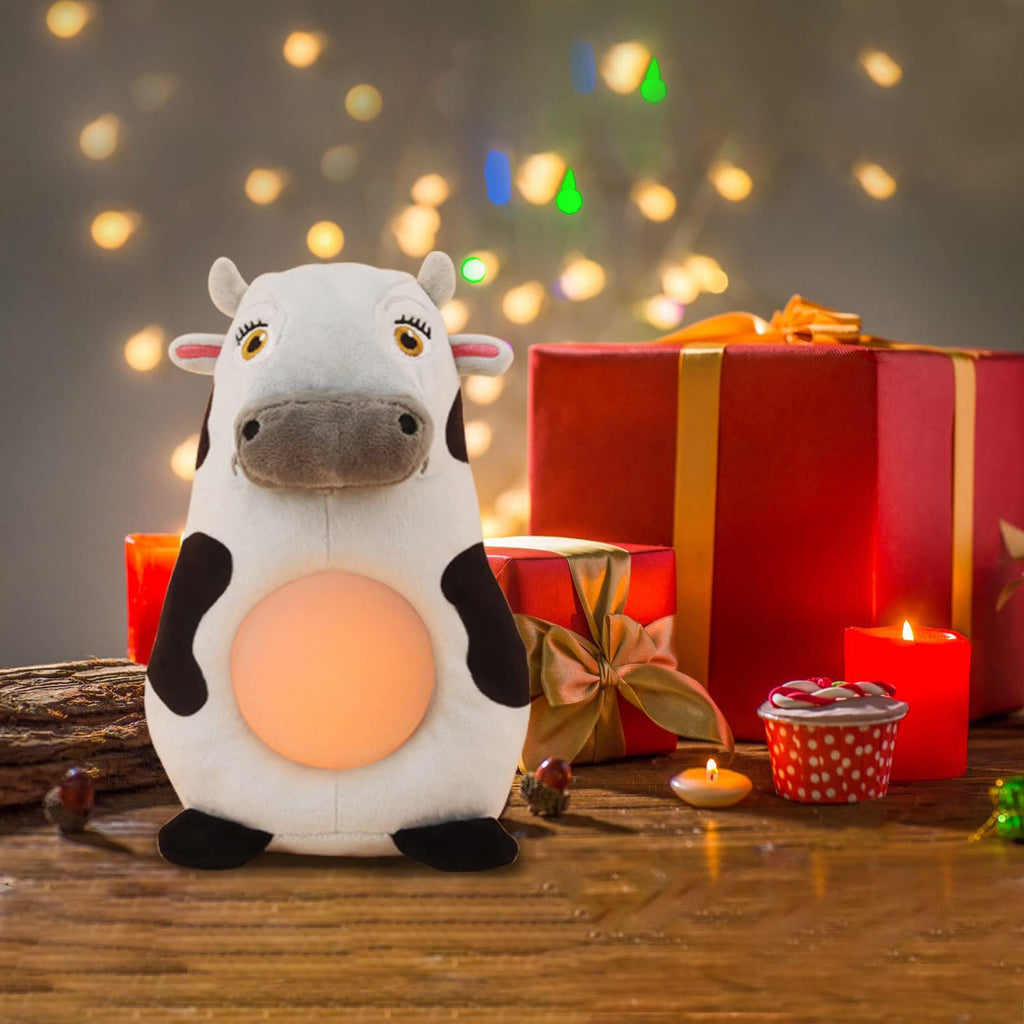 Musical cow toy displayed as a potential gift, with a festive background including Christmas lights, candles, and gift boxes.